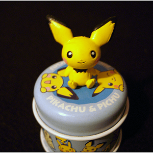 A close-up of my Pichu tin. It's very small, so it doesn't hold much, but it's so cute! :D There's the Pichu figure on top, plus the Pichu design on t